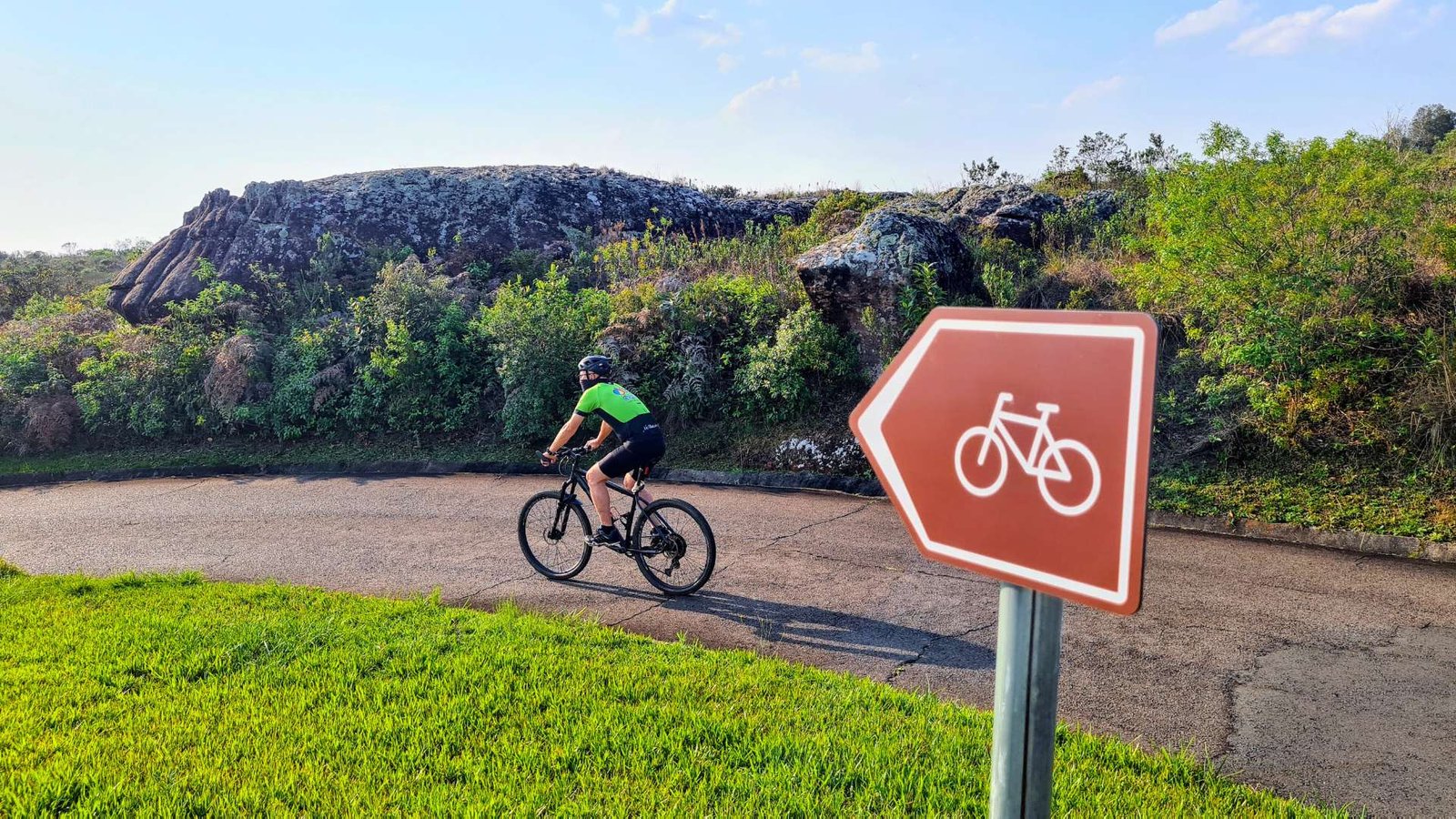O ciclista pedala e contempla o cicloturismo autoguiado através da sinalização direcional.