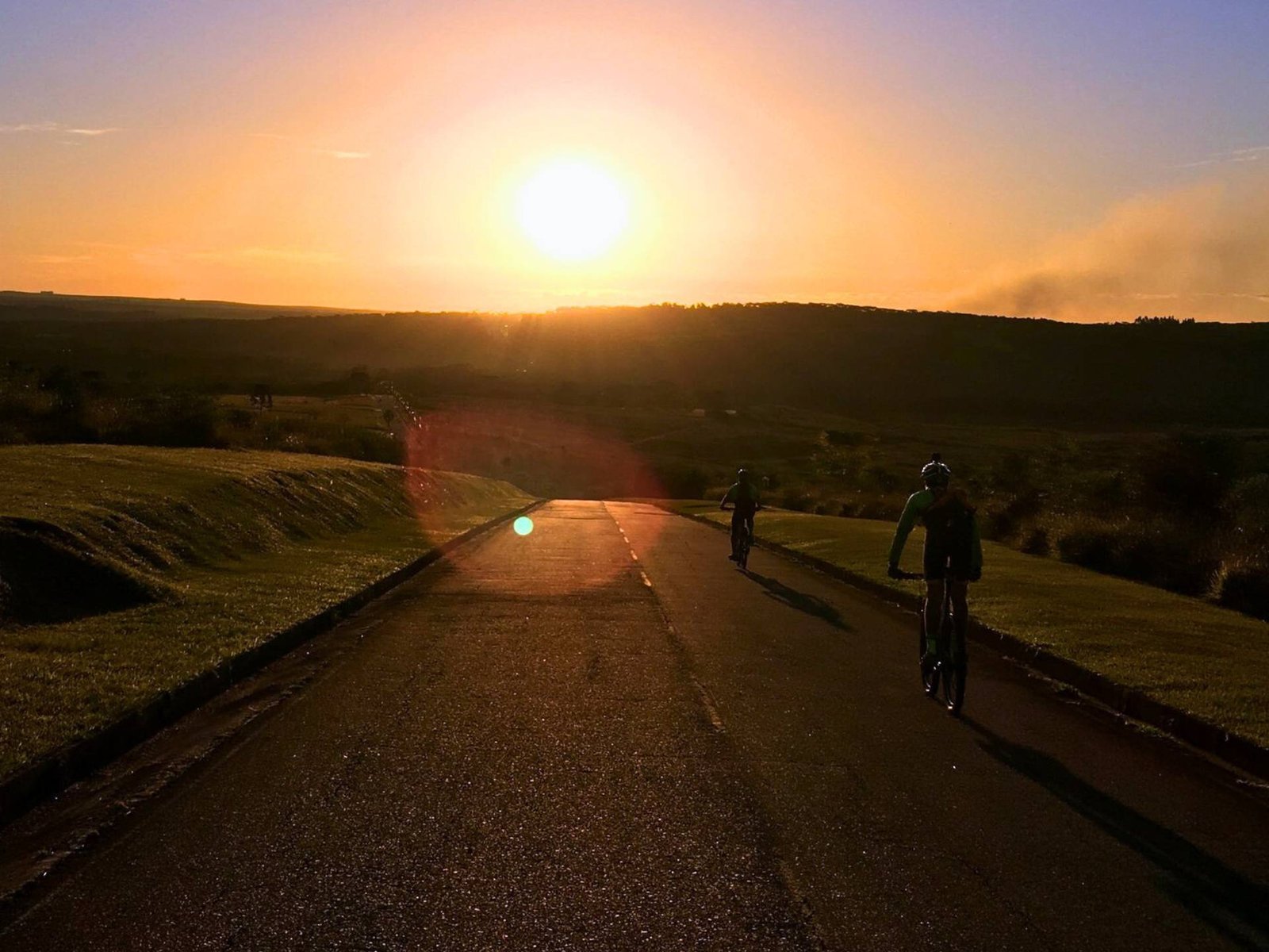 Ciclistas pedalam em direção ao horizonte com o deslumbrante pôr do sol no Dia Nacional do Ciclista. 