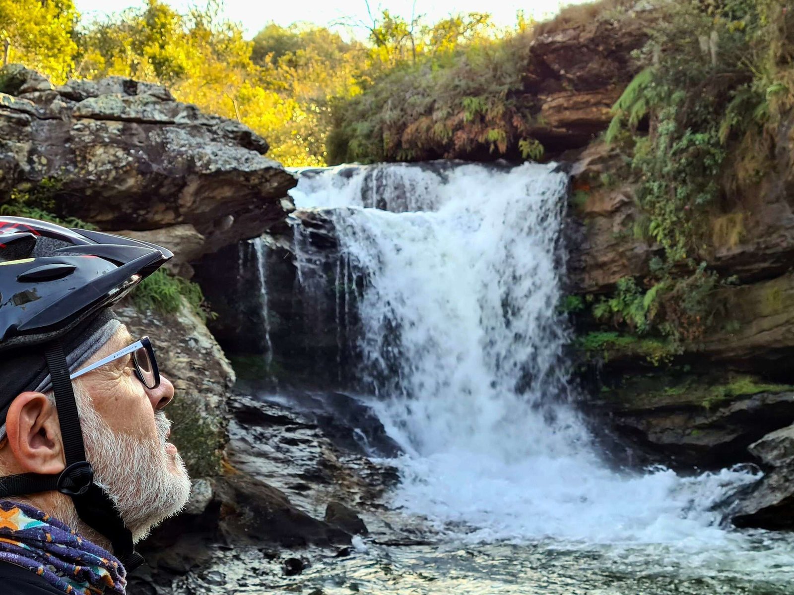 Ciclista contempla a cachoeira e se inspira na natureza exuberante.