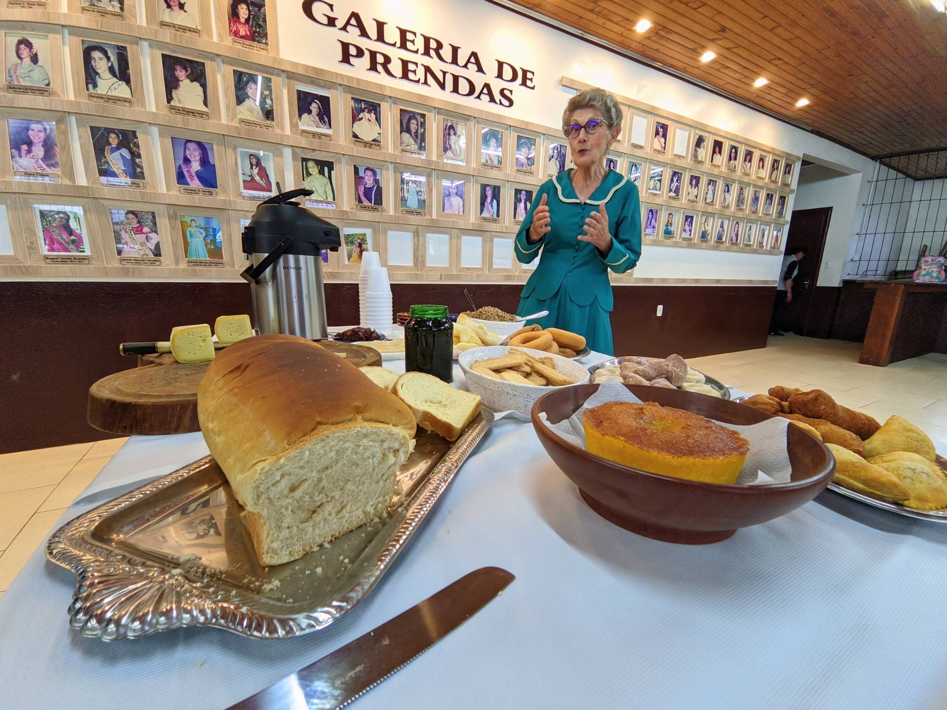 Mesa preparada carinhosamente: "O Papel das Mulheres na Rota dos Tropeiros" e a galeria de prendas homenageadas.