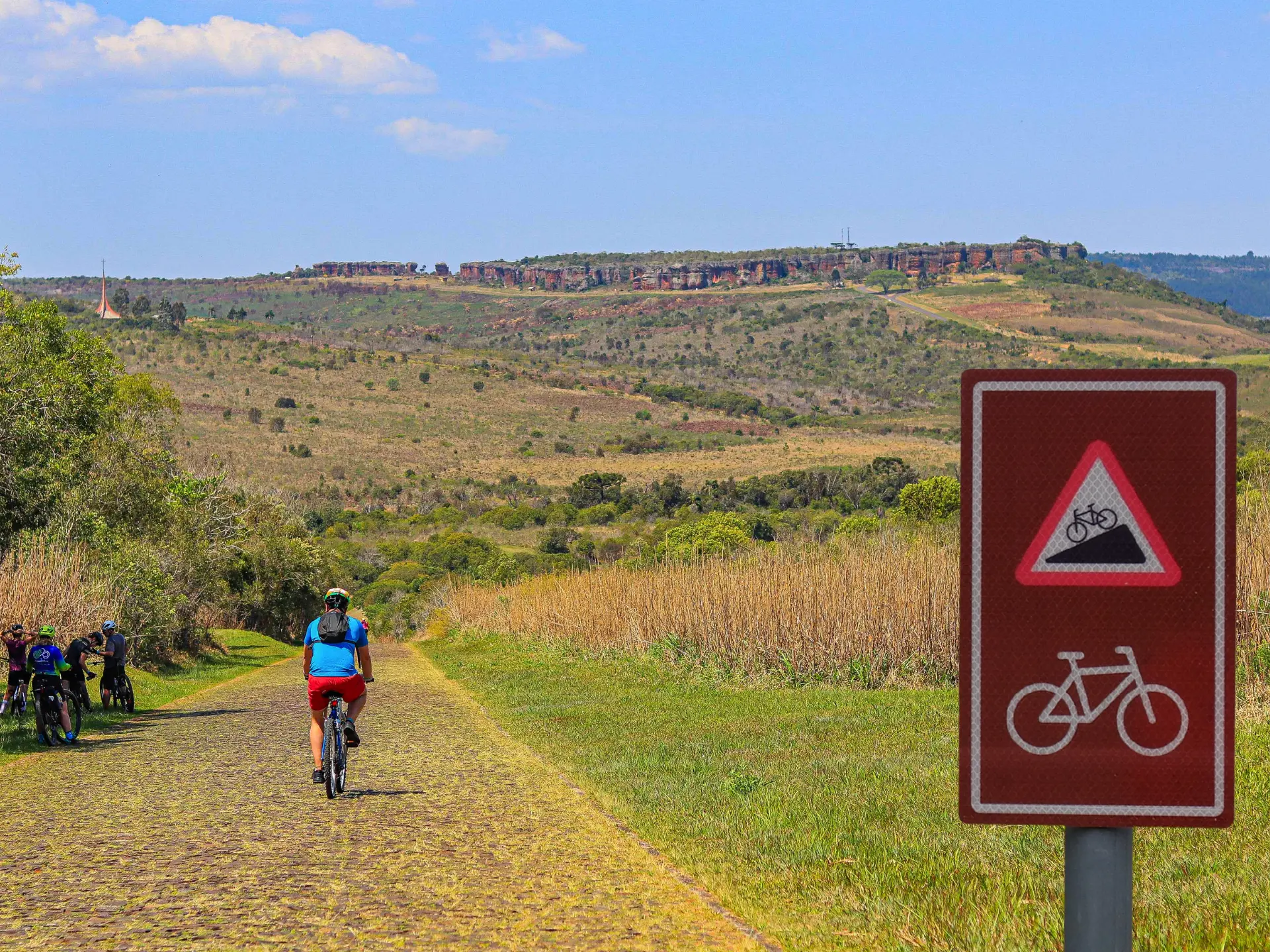 Ciclistas pedalando na Rota dos Tropeiros com sinalização marrom de cicloturismo autoguiado no Parque Estadual Vila Velha, unidade de conservação nos Campos Gerais do Paraná. Foto: Ivan Mendes © Lobi Ciclotur